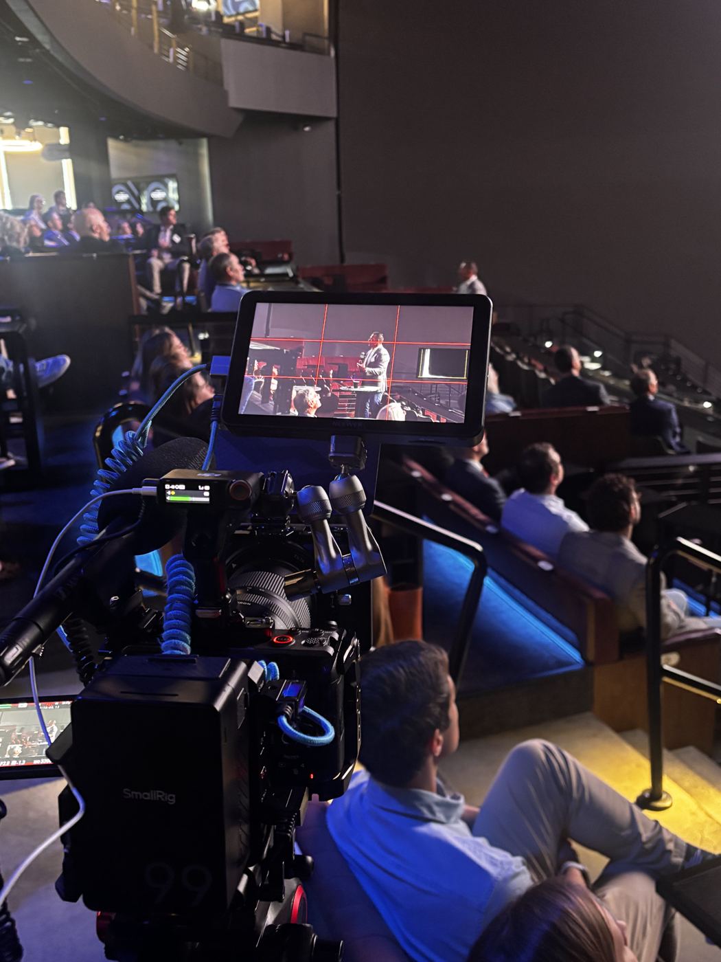 Jake filming a speaker at a conference at Cosm, with the shot on a field monitor