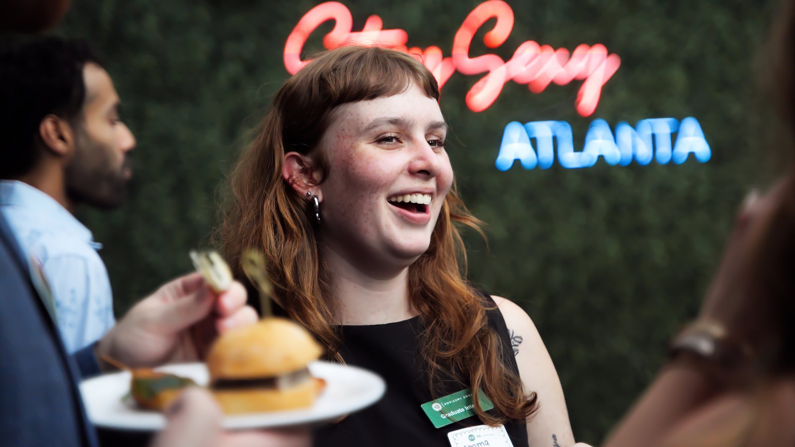 A guest laughing with a slider in hand at KB Advisory Group's 25th anniversary