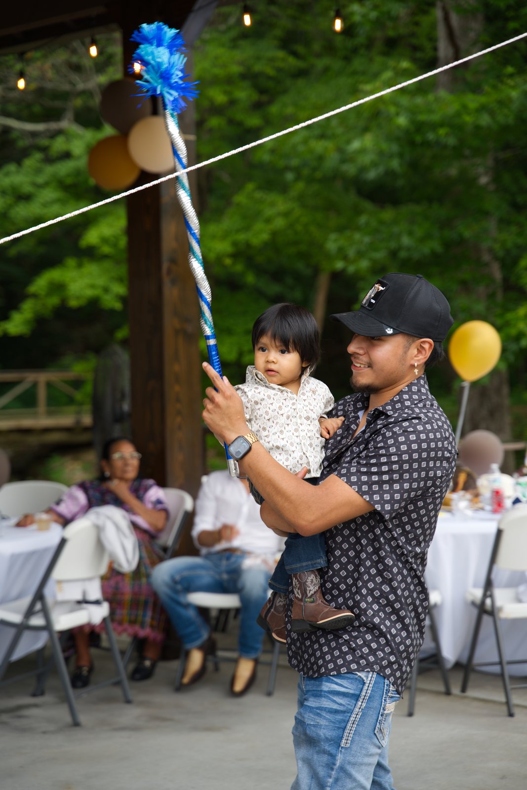 A dad holding his son by the piñata